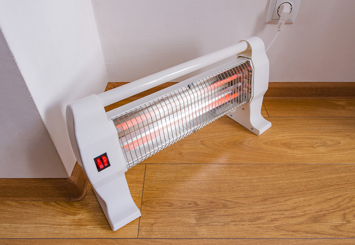 Electric halogen heater at home. Heating the apartment in cold autumn or winter time.